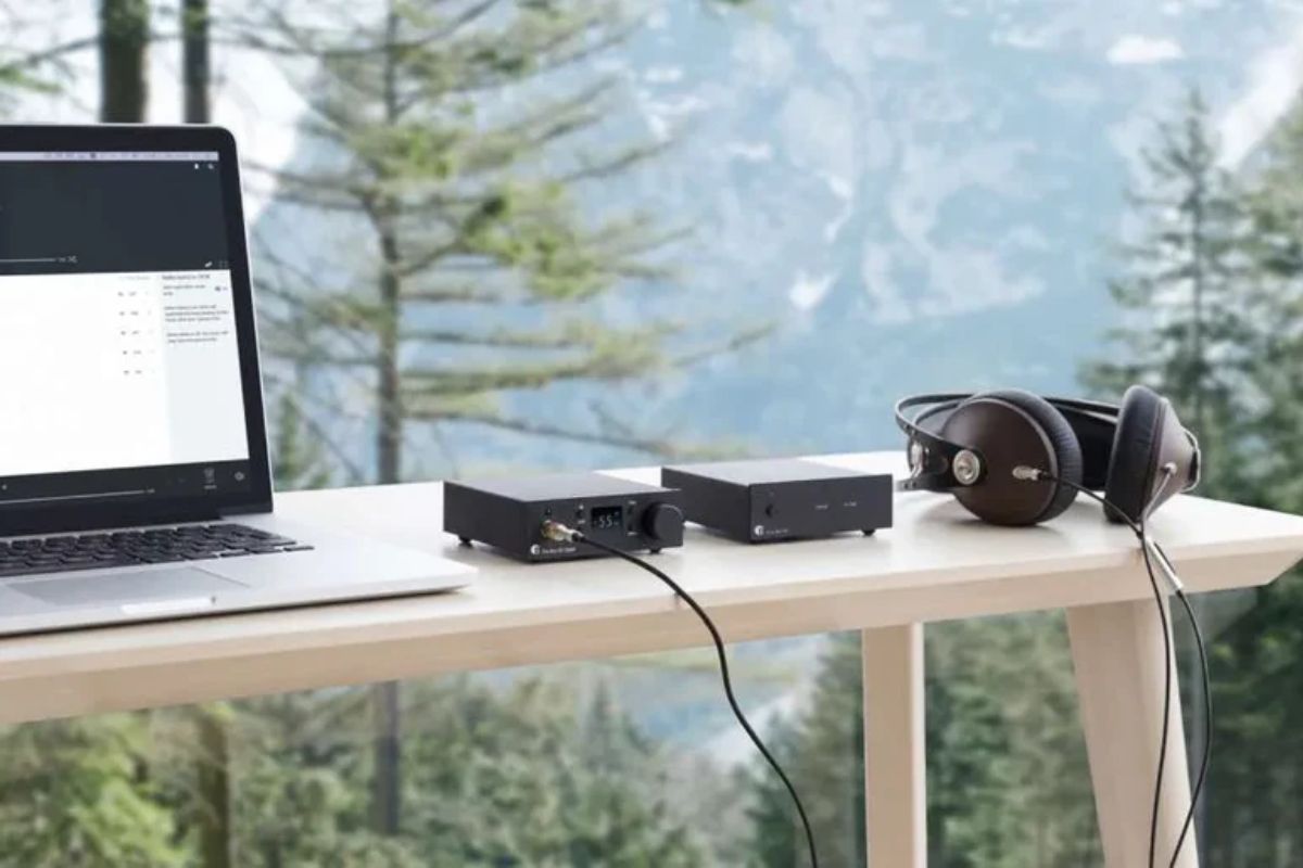 Kompakte HiFi-Komponenten und Kopfhörer auf einem Tisch neben einem Laptop