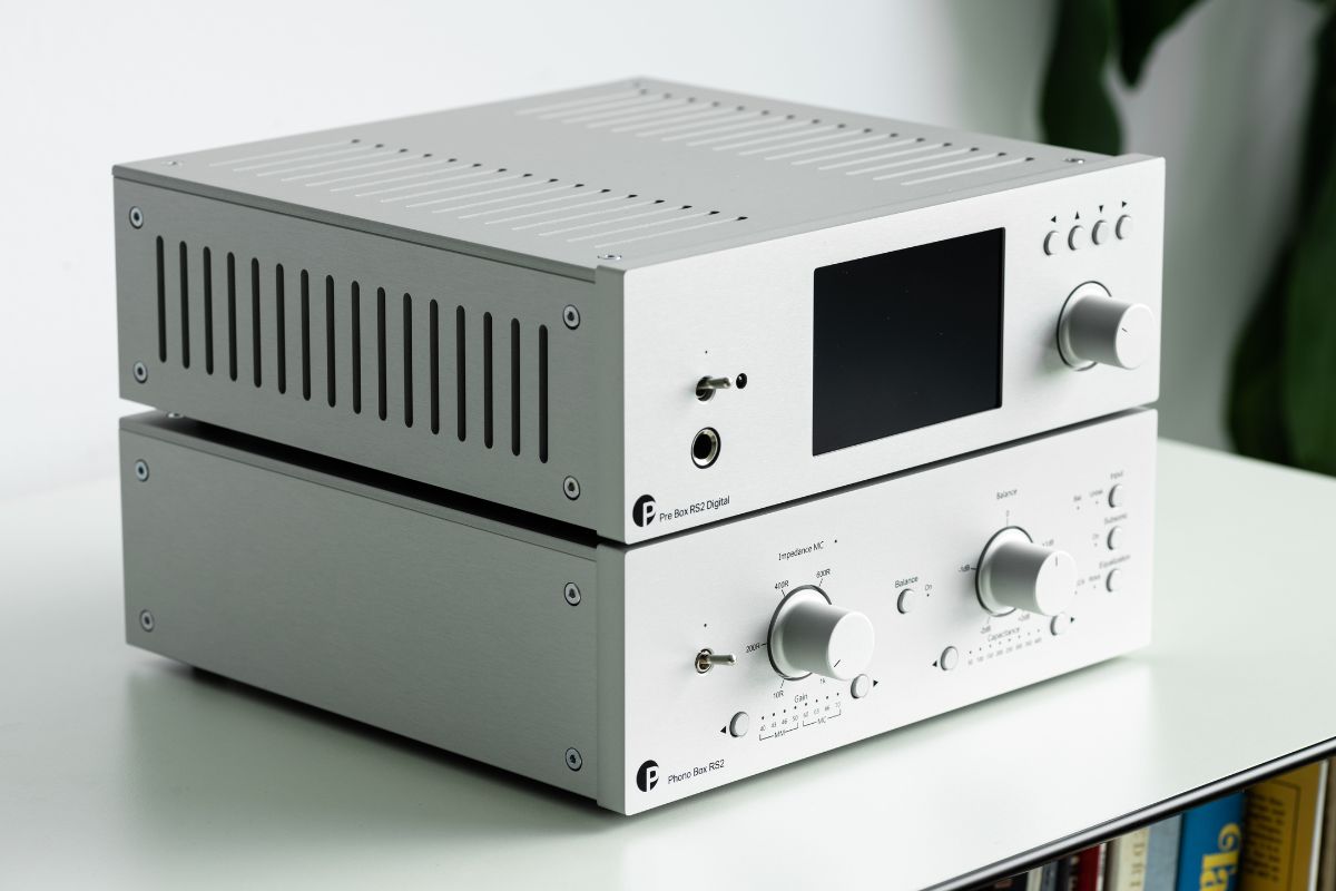 Zwei silberne HiFi-Komponenten von Pro-Ject stehen übereinander auf einem weißen Regal. Oben befindet sich die Pre Box RS2 Digital mit Display und Drehregler, darunter die Phono Box RS2 mit Reglern und Schaltern für Ton- und Balance-Einstellungen.
