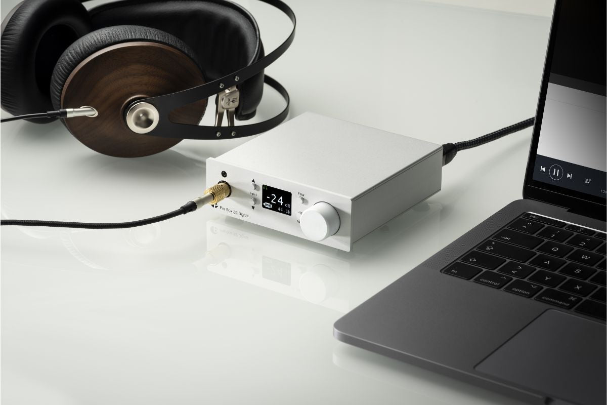 Hochwertiger DAC/Kopfhörerverstärker mit Laptop und Over-Ear-Kopfhörern auf einem weißen Tisch